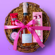 Gift basket with a bottle of Lauderhu, pink ribbon, and snacks on a purple background