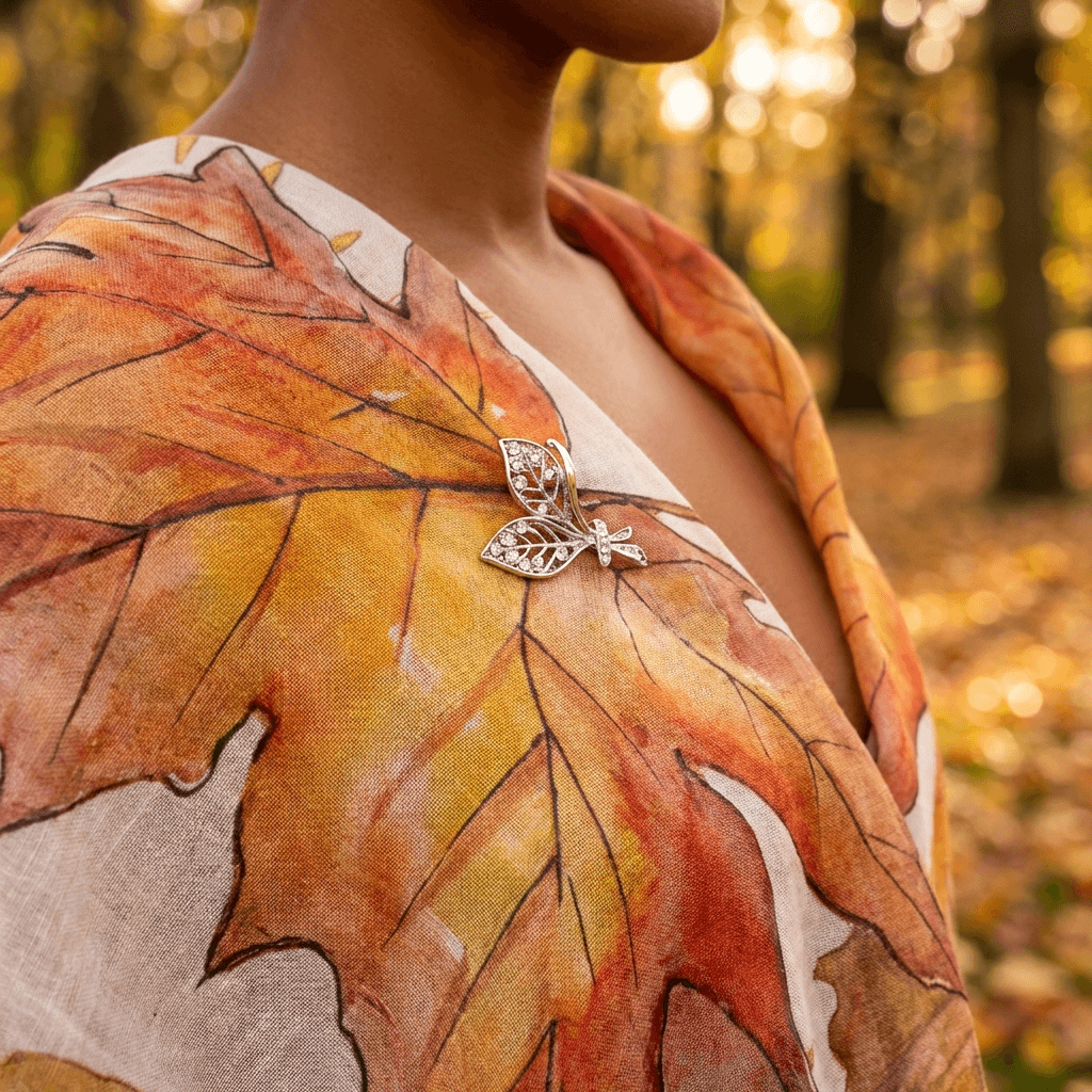 Person wearing a shirt with autumn leaf design and a butterfly brooch in a forest setting