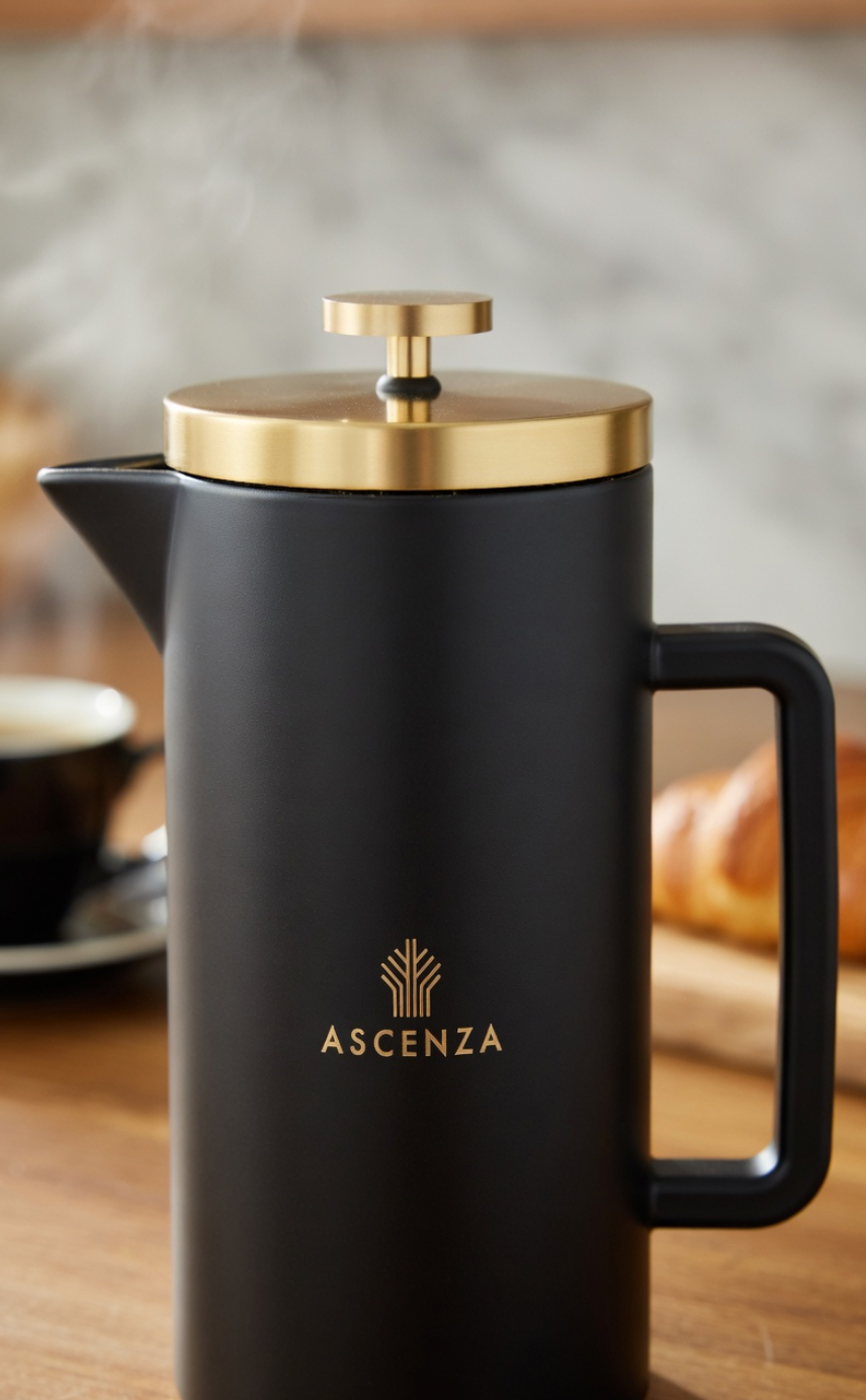 Black coffee press with gold lid on a wooden surface, featuring the Ascenza brand.