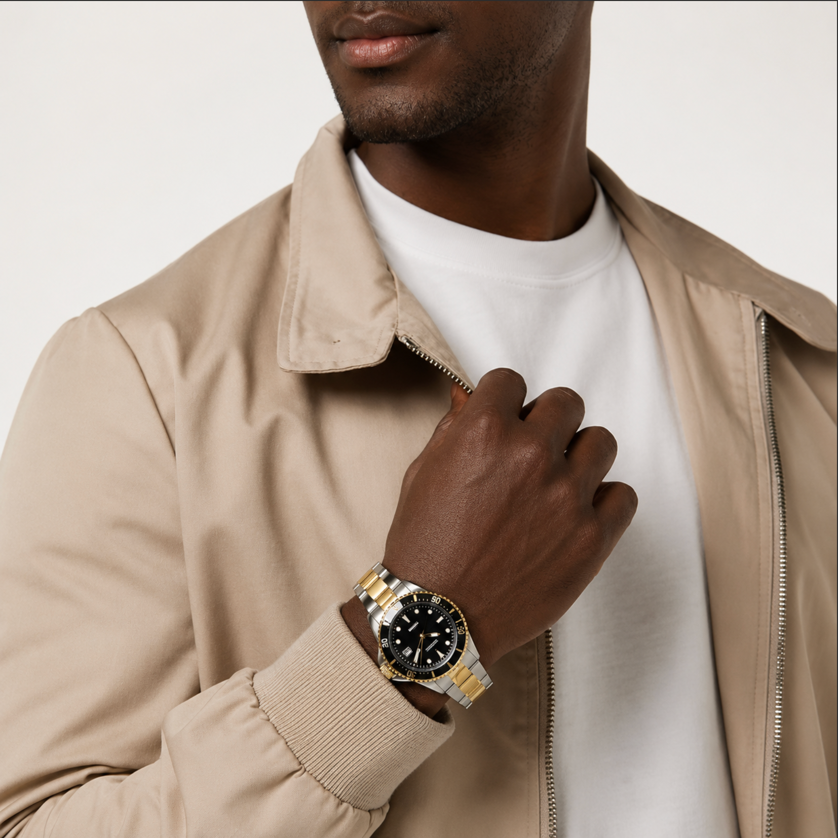 Man wearing a beige jacket and white shirt with a gold watch on his wrist.