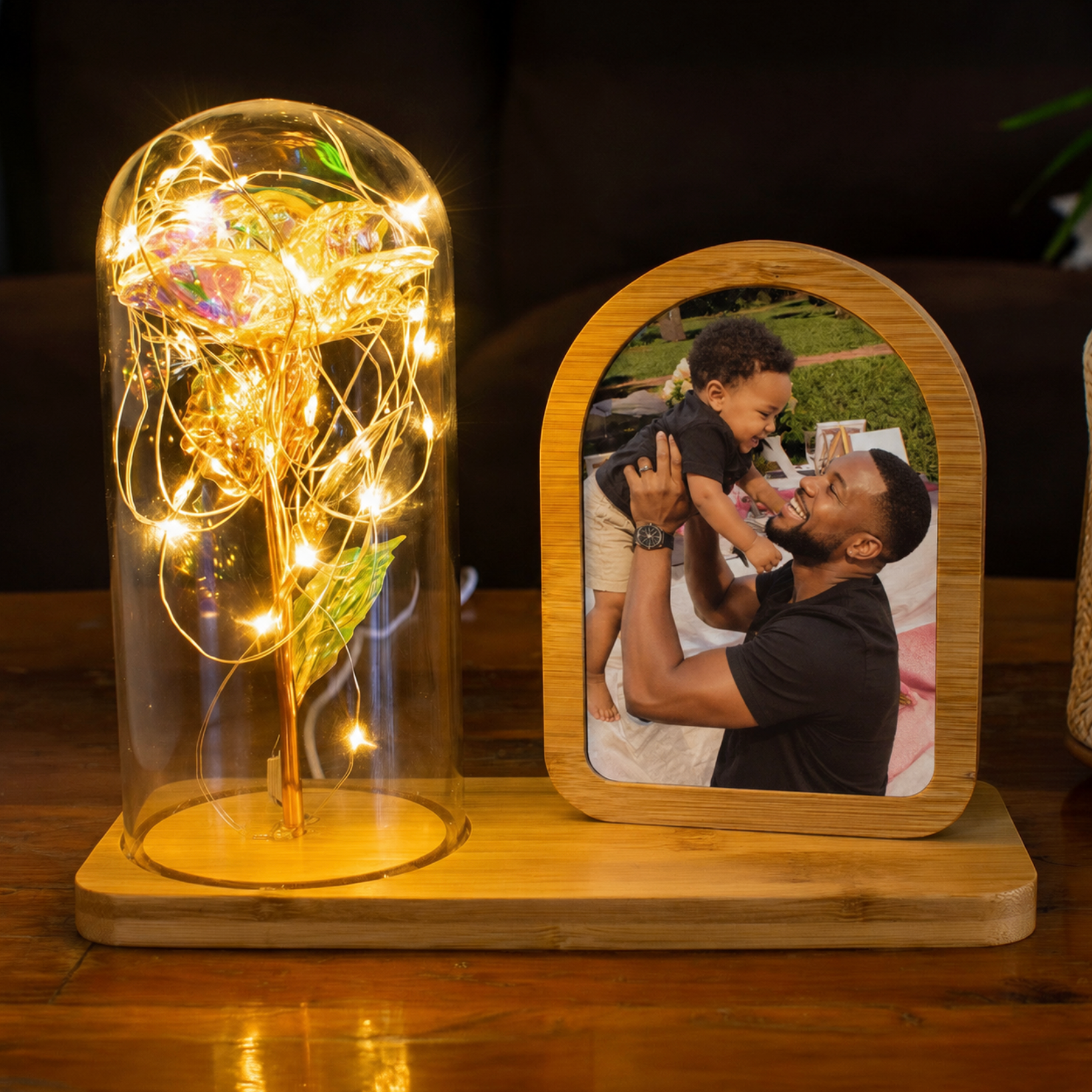 Decorative lamp with string lights and a photo frame with a father and child picture on a wooden surface.