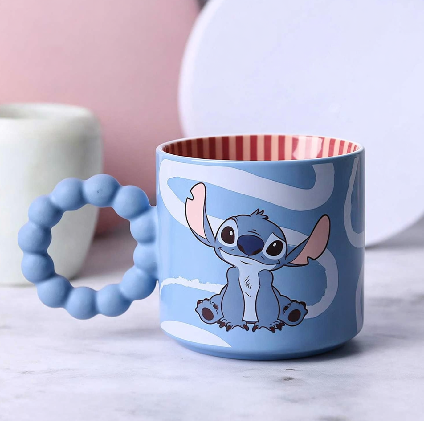 Blue mug with cartoon character handle on a marble surface