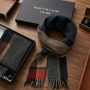 Scarf with plaid pattern on a wooden surface, featuring 'equilibrium' branding.