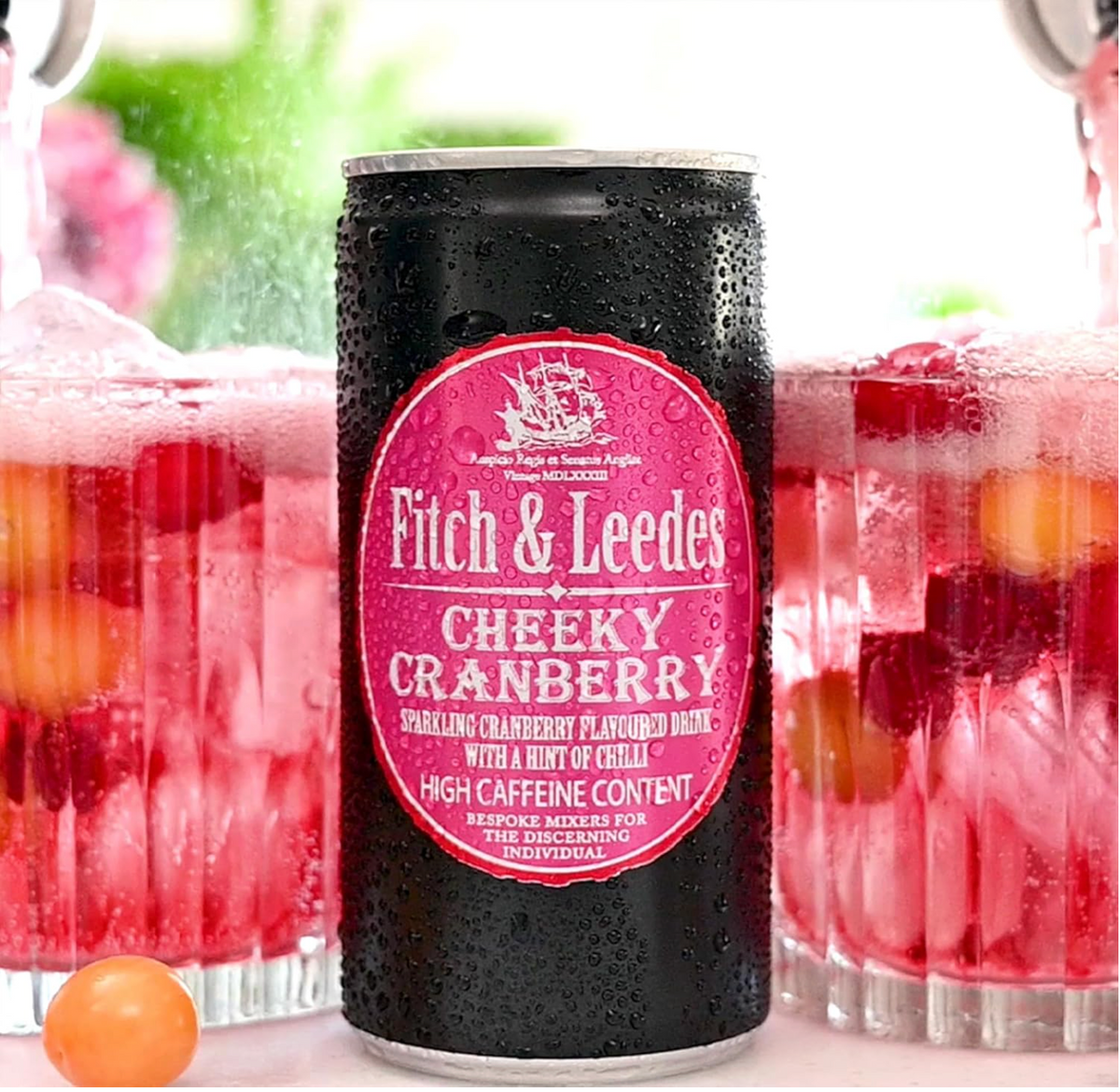 Fitch & Leedes Cheeky Cranberry can with glasses of cranberry juice in the background