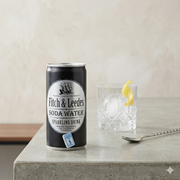 Fitch & Leedes soda water can on a concrete surface with a glass of cocktail.