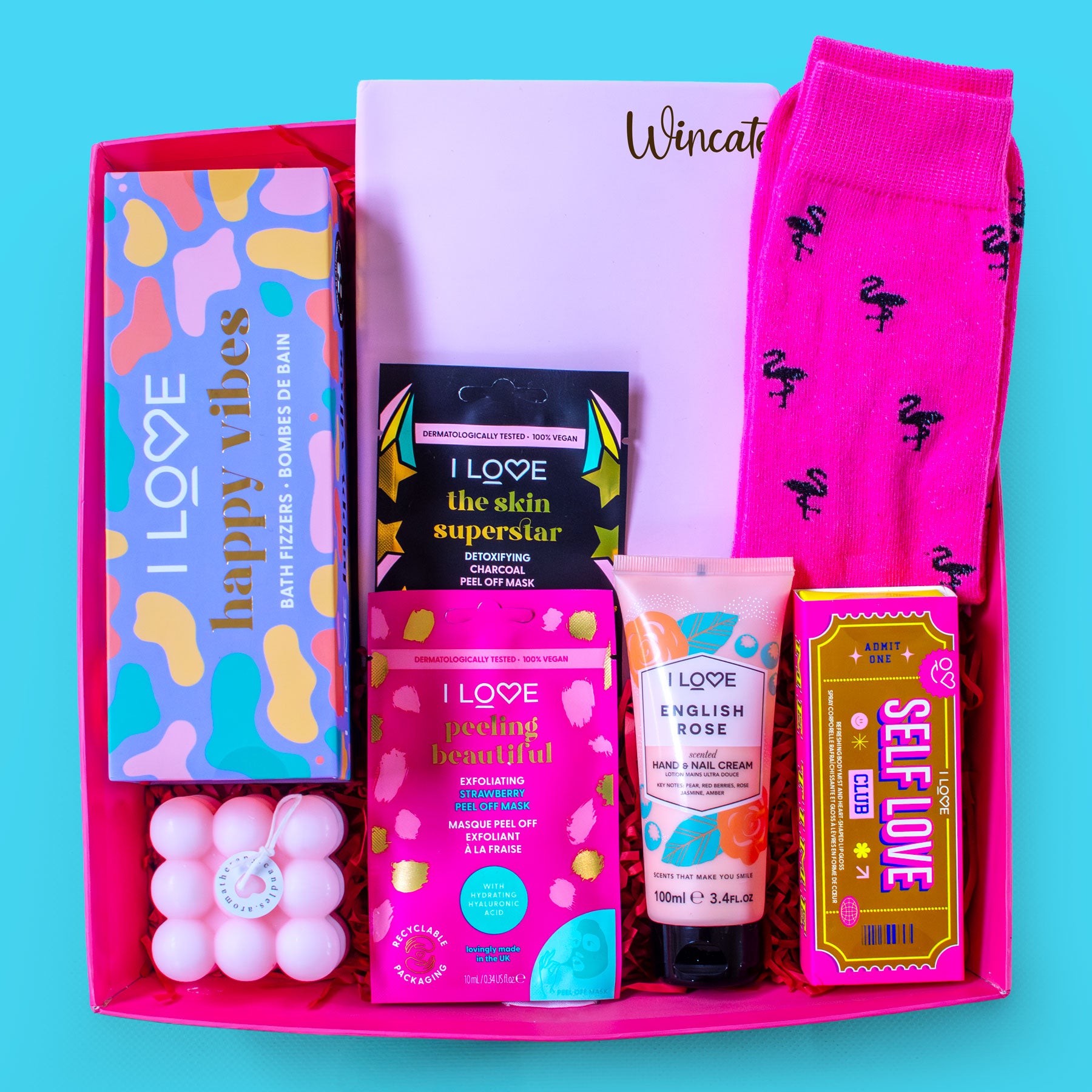 Assorted beauty and self-care products in a pink box on a blue background