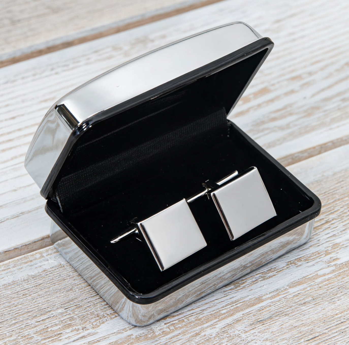 Silver tie clip in an open black box on a wooden surface