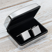 Silver tie clip in an open black box on a wooden surface