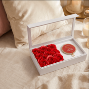 Valentine's Day gift set with red roses in a box and a decorative tag on a bed.