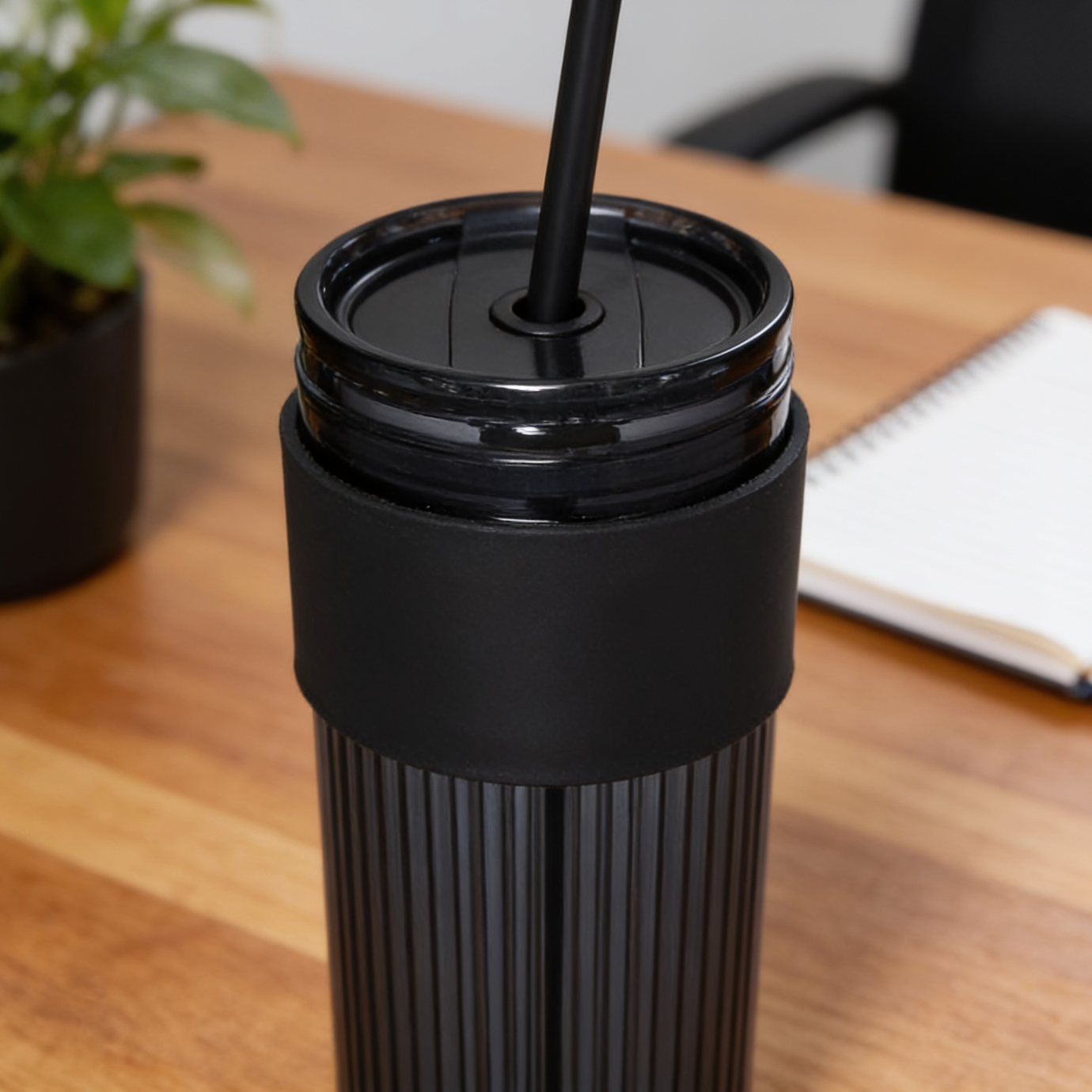 Black travel mug with a straw on a wooden table