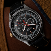 Luxury watch with detailed face and brown leather strap on a textured surface