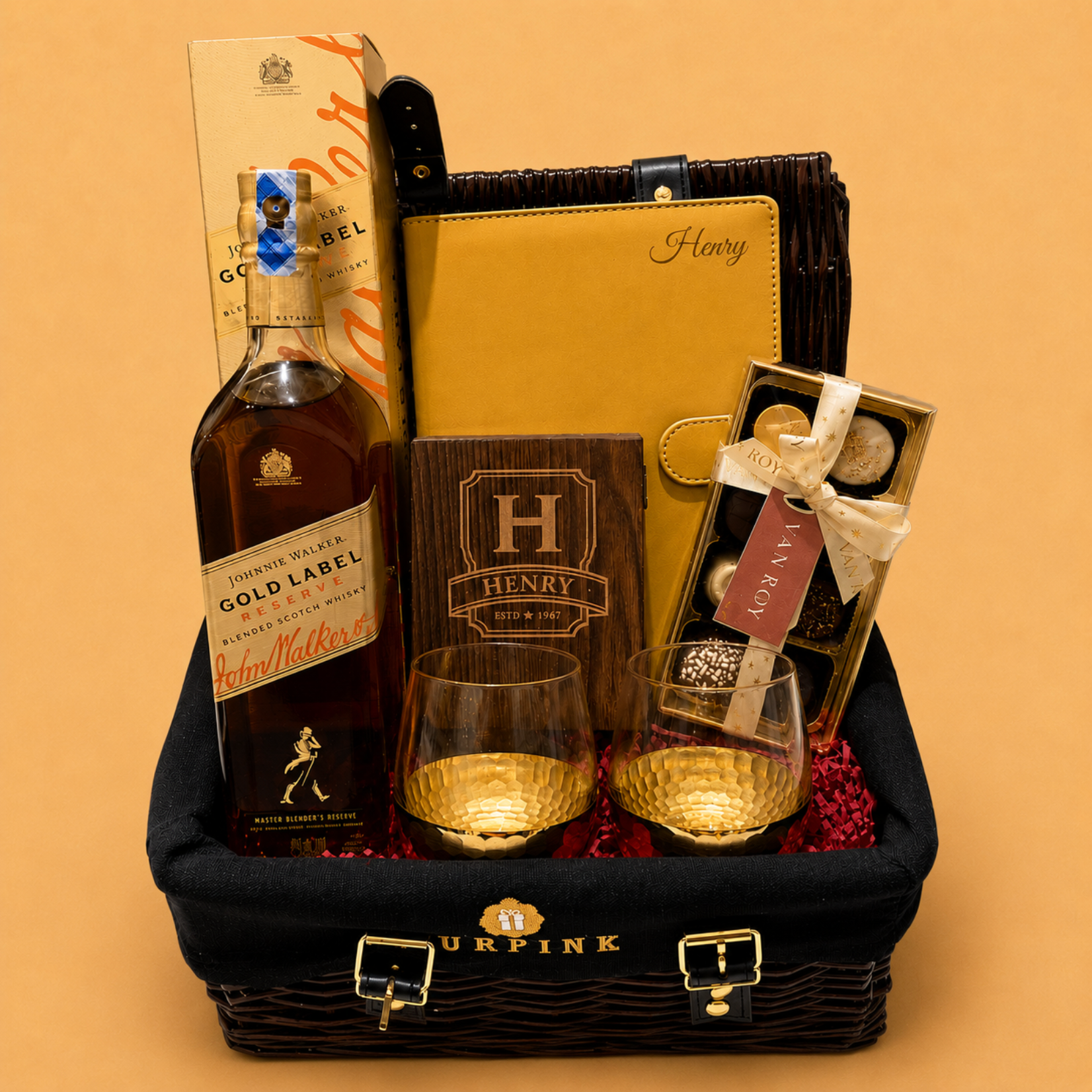 Gift basket with Johnnie Walker Gold Label whisky, glasses, and chocolates on a beige background