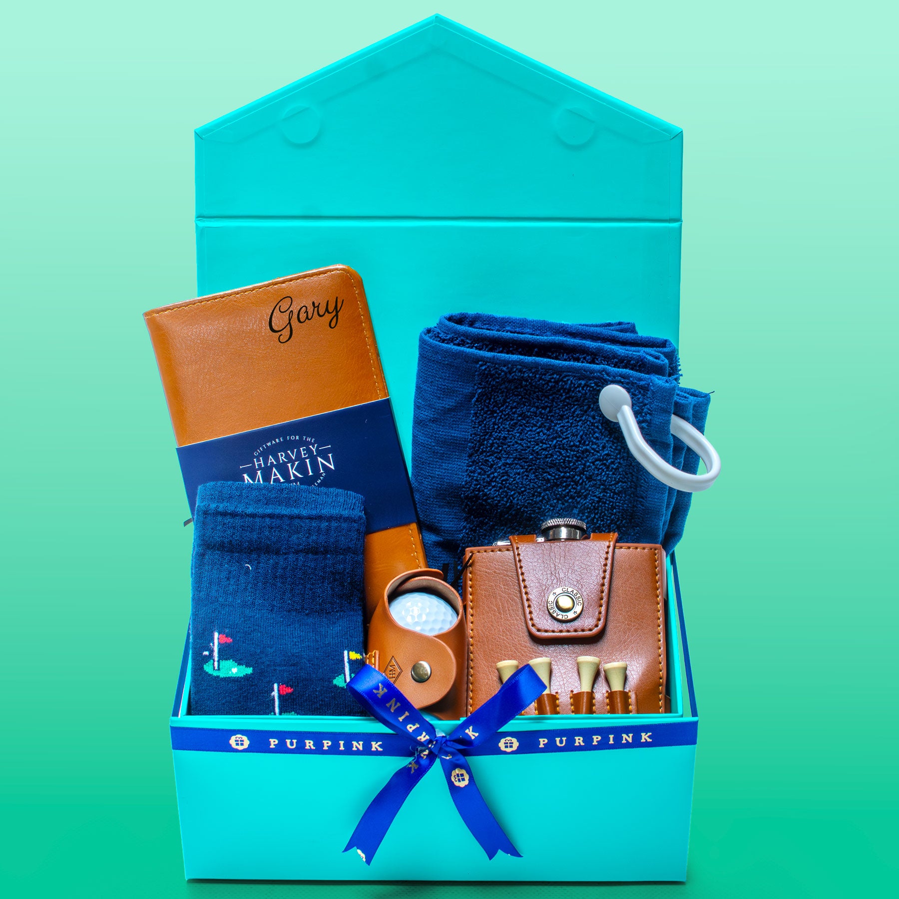 Gift set with leather wallet, socks, and flask in a blue box on a green background