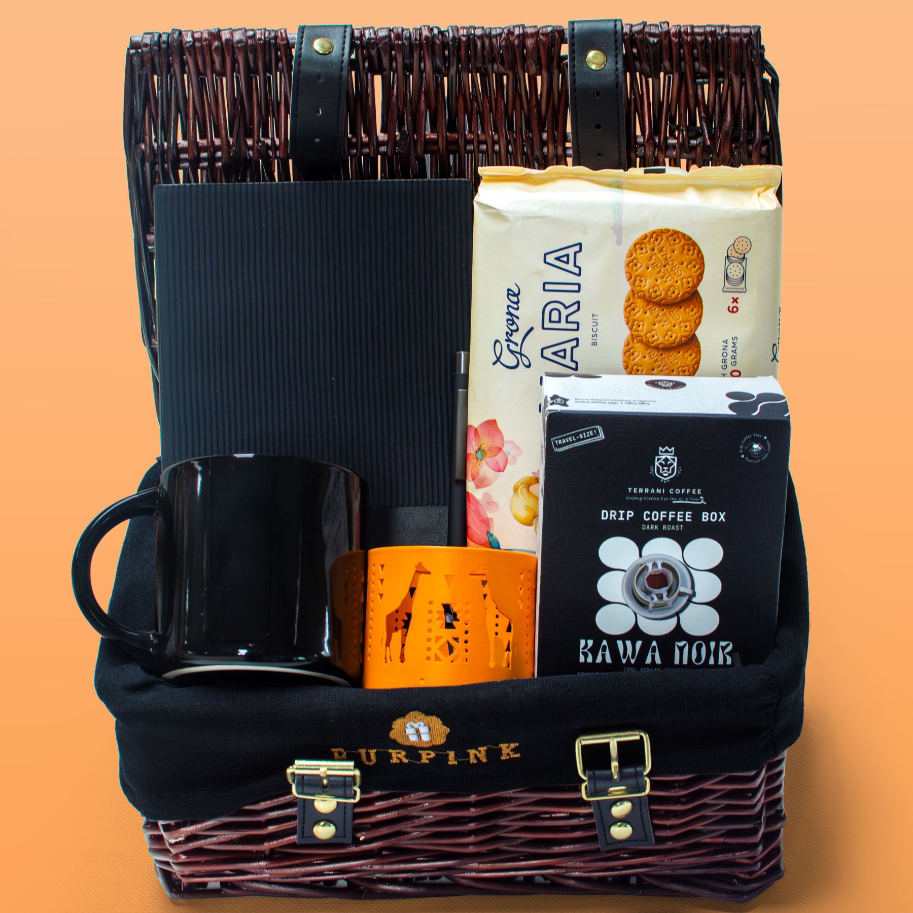 Gift basket with coffee items including a mug, coffee beans, and a coffee box on an orange background.