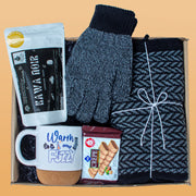 Gift box with gloves, mug, cookies, and coffee package on a beige background