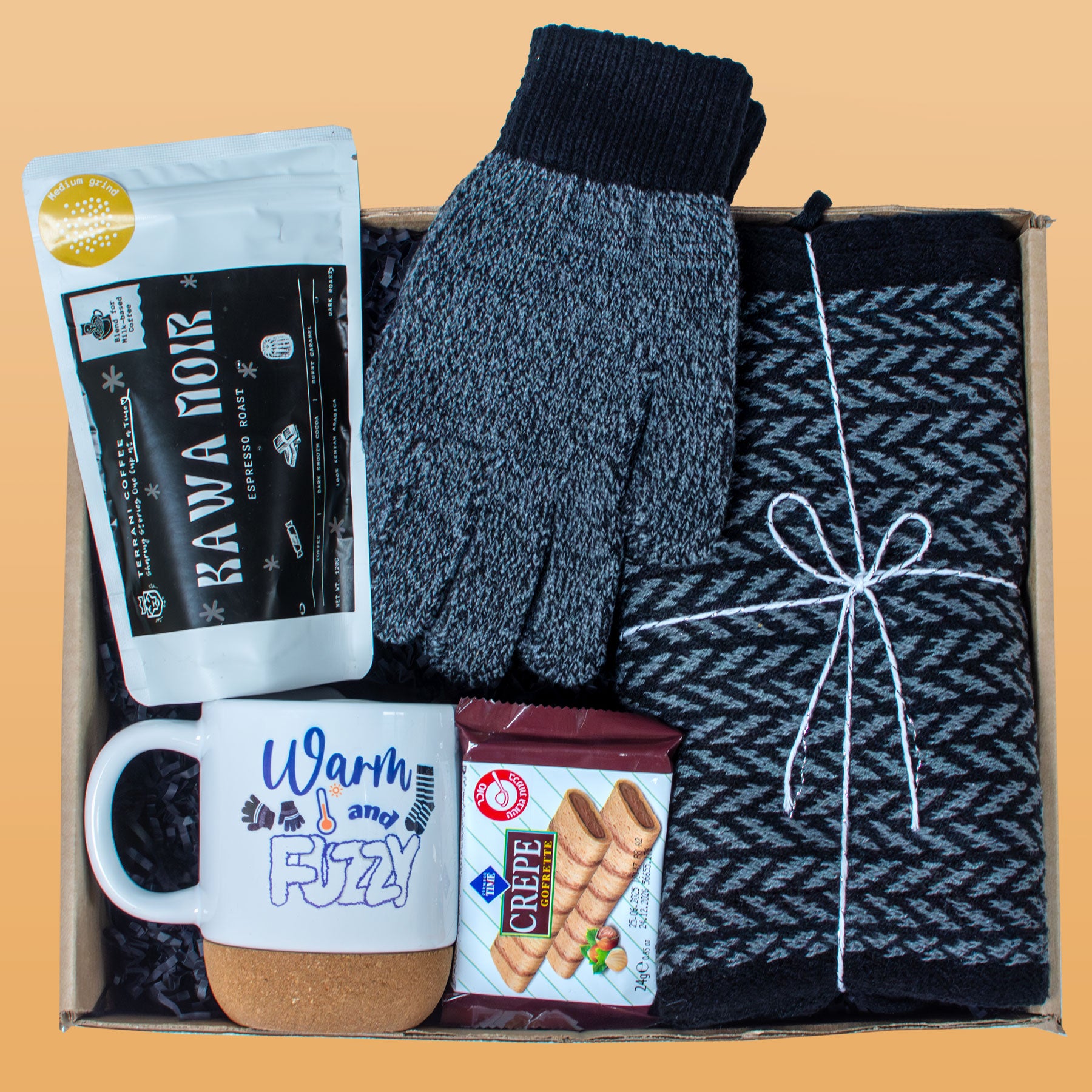 Gift box with gloves, mug, cookies, and coffee package on a beige background