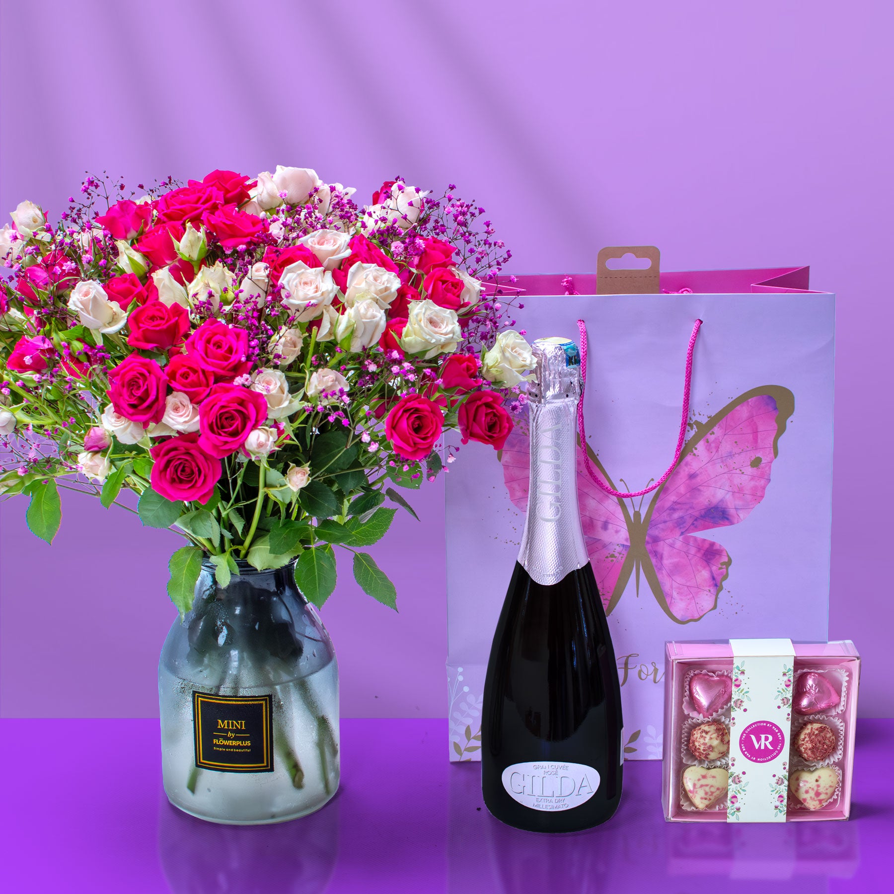 Bouquet of flowers, champagne bottle, and chocolate boxes on a purple background