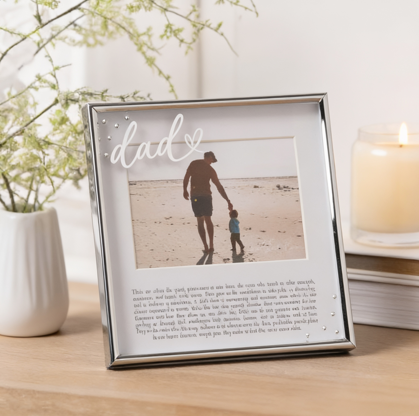 Framed photo of a man and child on a beach with 'dad' above, on a wooden surface.