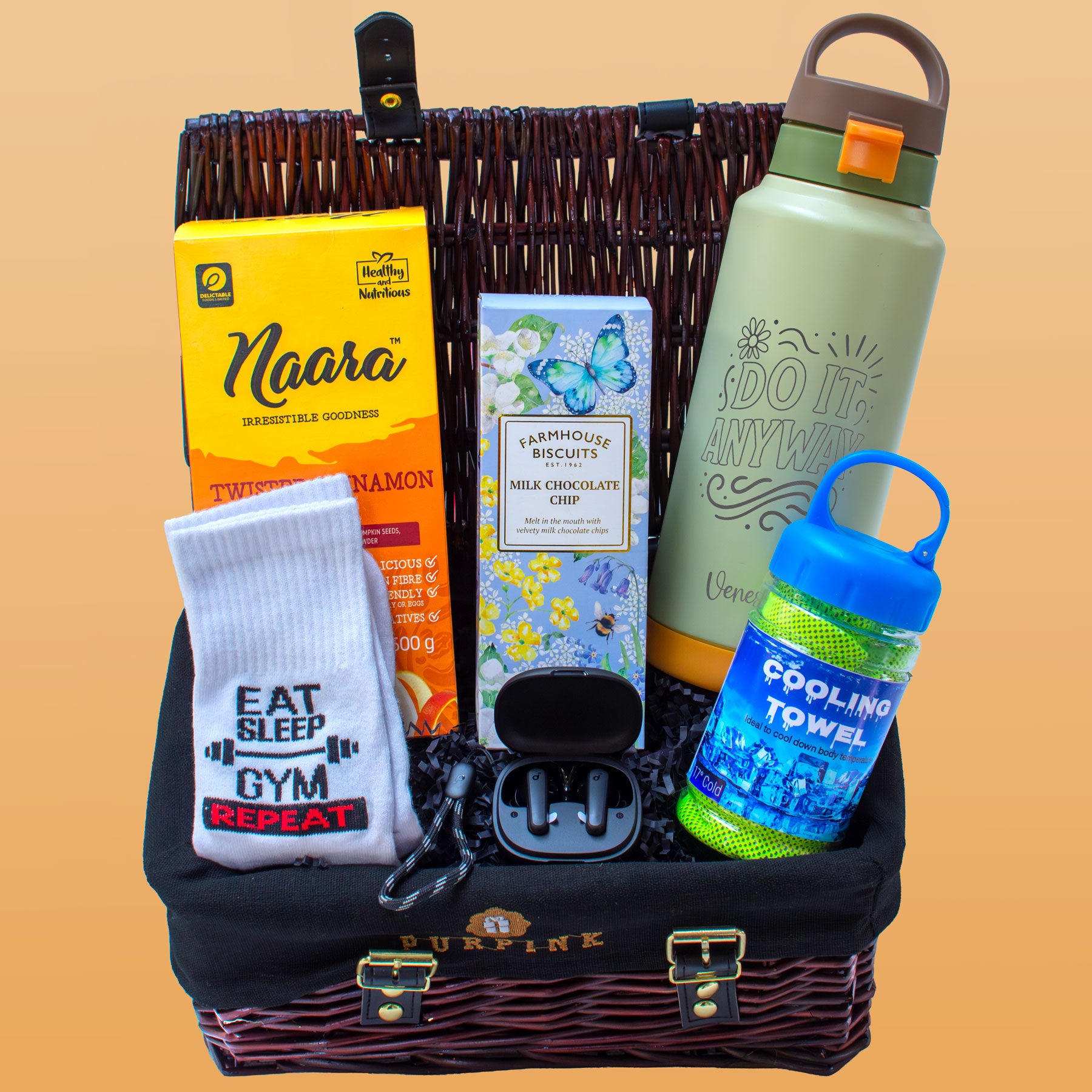 Basket with Naara biscuits, sock, hair accessories, water bottle, and cooling towel on a beige background