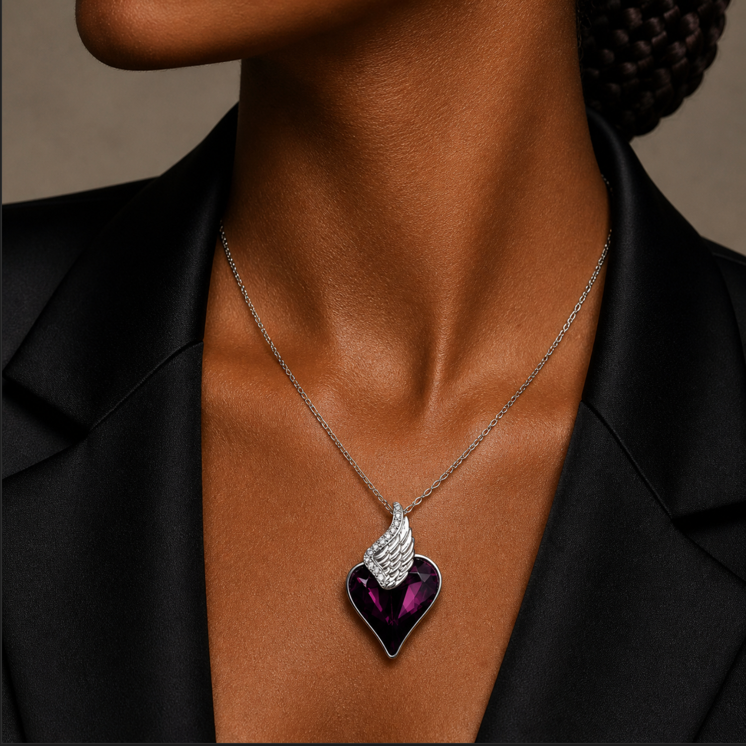 Necklace with a heart-shaped pendant featuring wings worn by a person against a neutral background