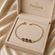 Gold bracelet with gemstones in a 'Purpink Gifts' box on beige fabric