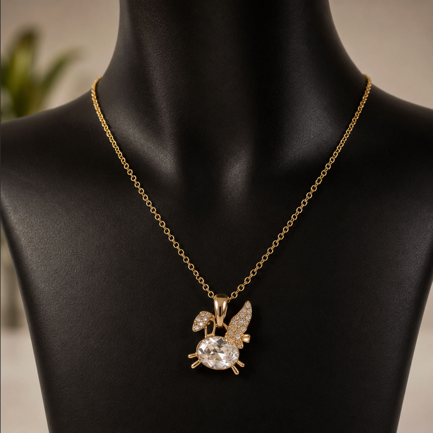 Gold necklace with a detailed pendant on a black mannequin