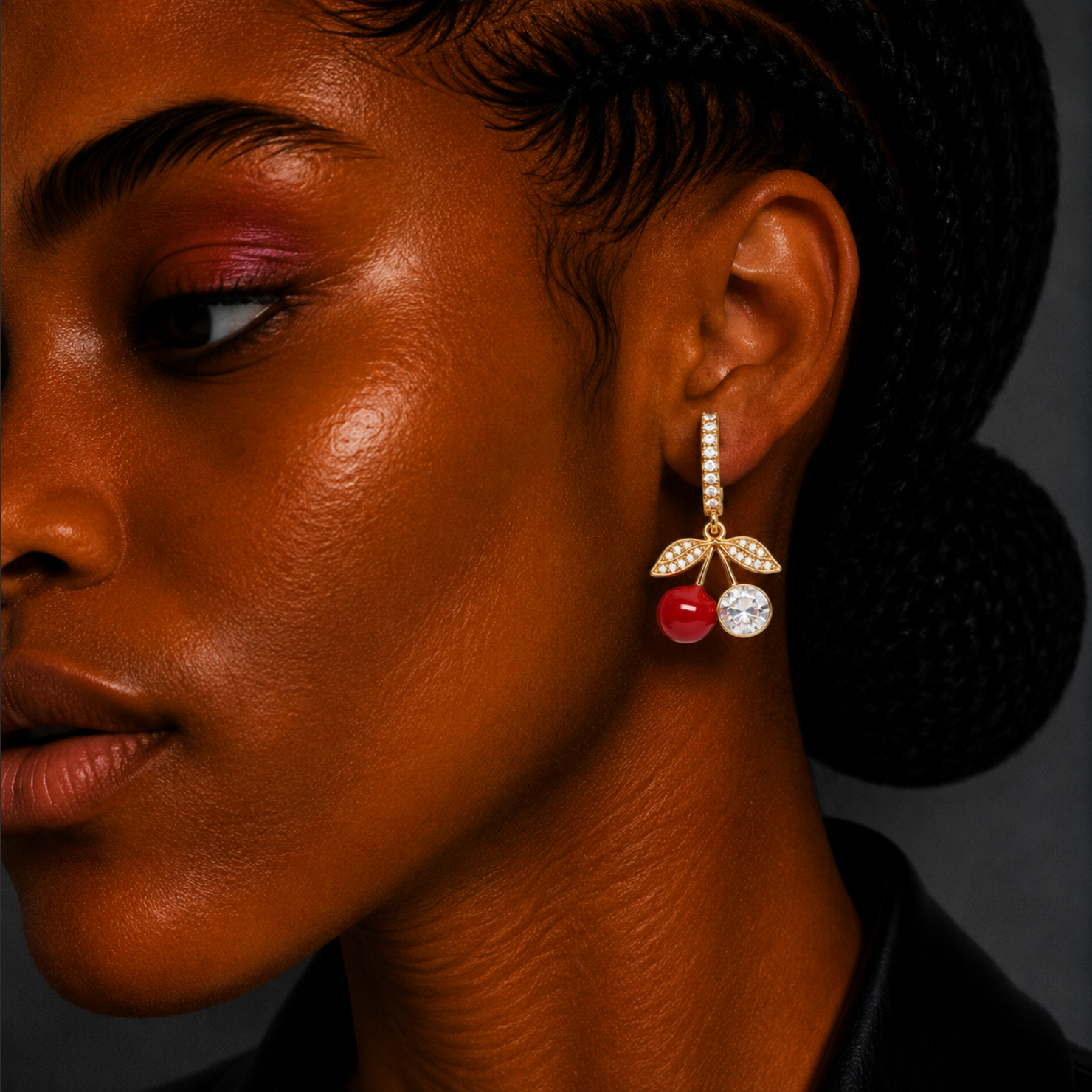 Close-up of a woman's face wearing a cherry-themed earring with a dark background