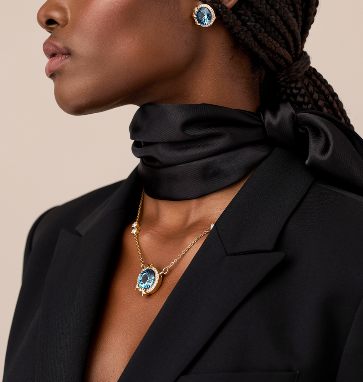Woman wearing a black outfit with jewelry including earrings and a necklace on a beige background