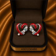 Heart-shaped earrings with red and silver design in a jewelry box on a brown fabric background