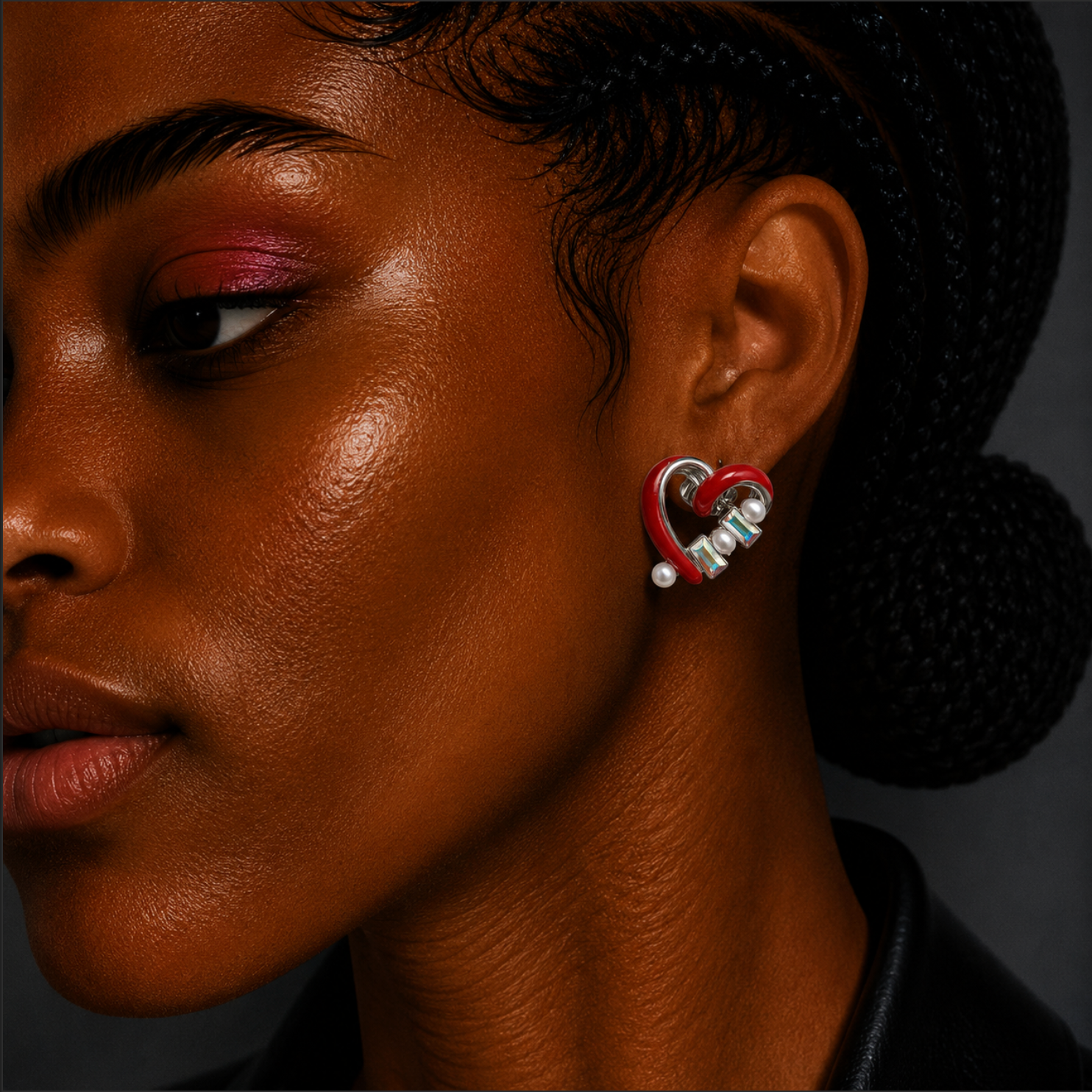 Close-up of a person wearing heart-shaped earrings with a dark background