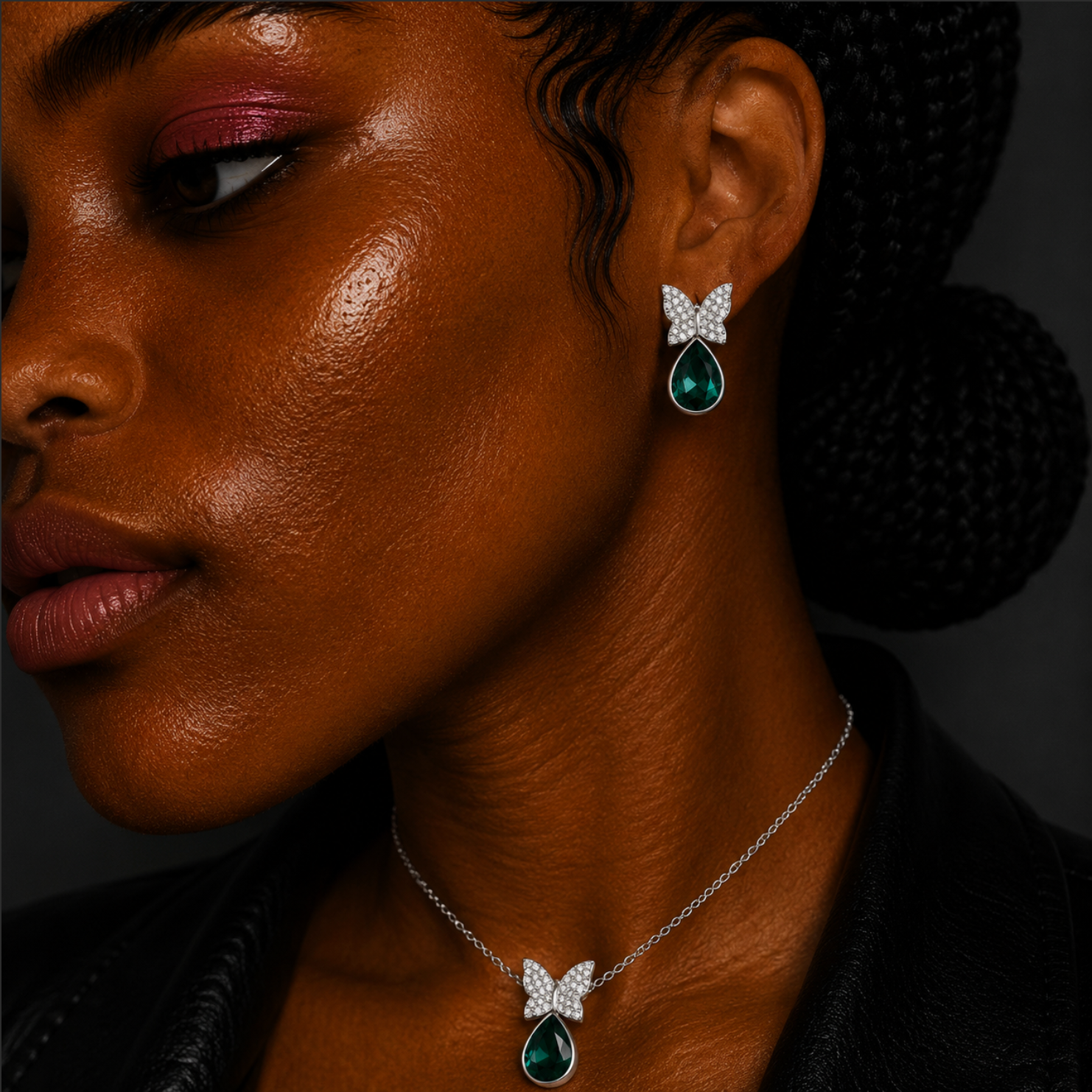 Close-up of a woman wearing emerald and diamond earrings and necklace against a dark background