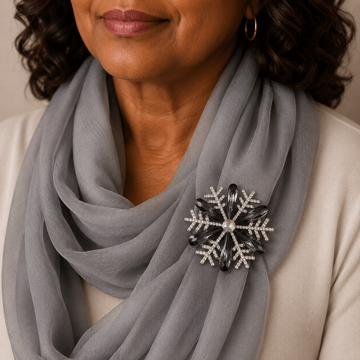 Woman wearing a gray scarf with a decorative snowflake brooch.
