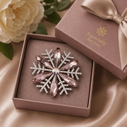 Snowflake-shaped jewelry in a gift box with a decorative bow and floral background