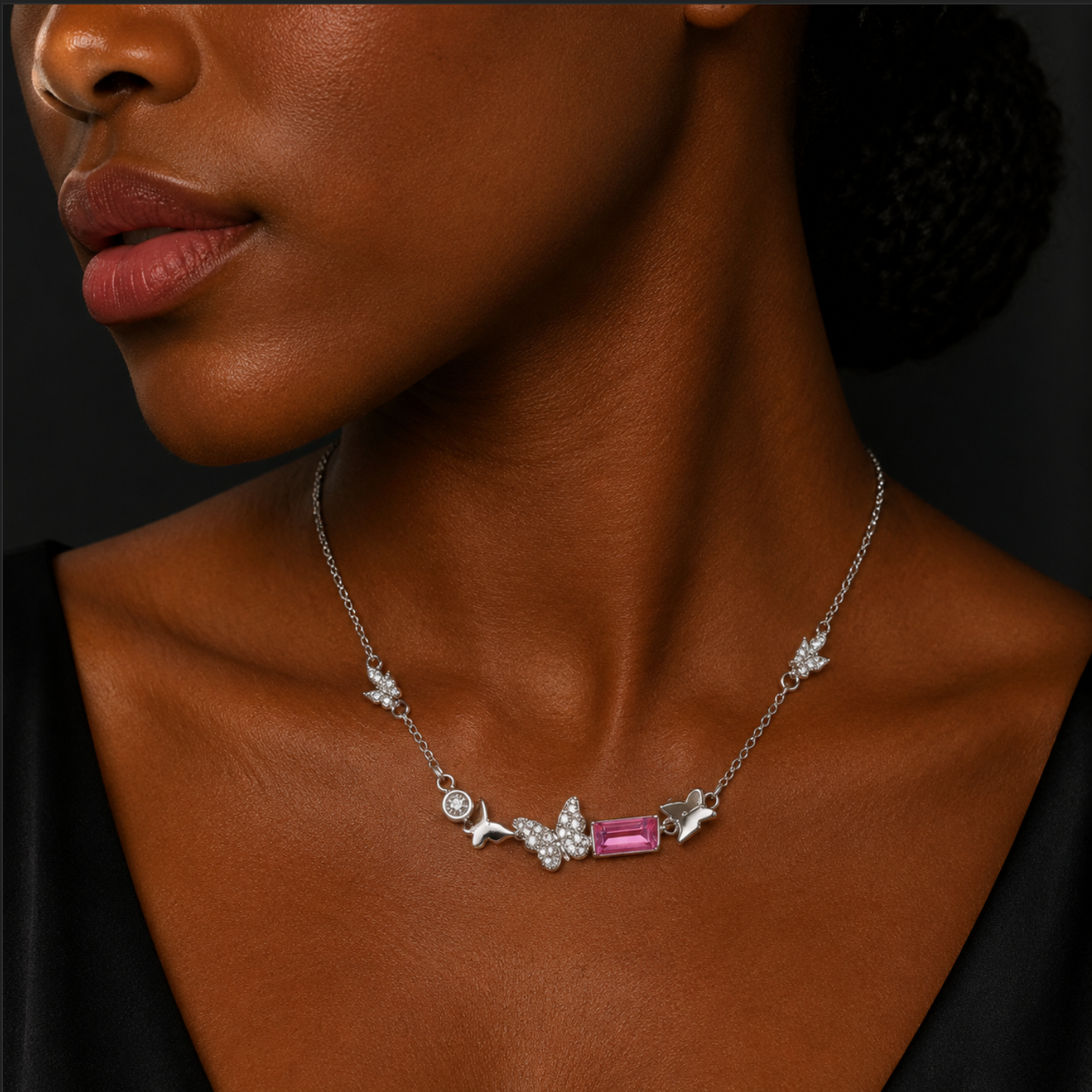 Close-up of a woman wearing a necklace with a pink gemstone on a dark background