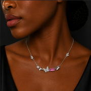 Close-up of a woman wearing a necklace with a pink gemstone on a dark background
