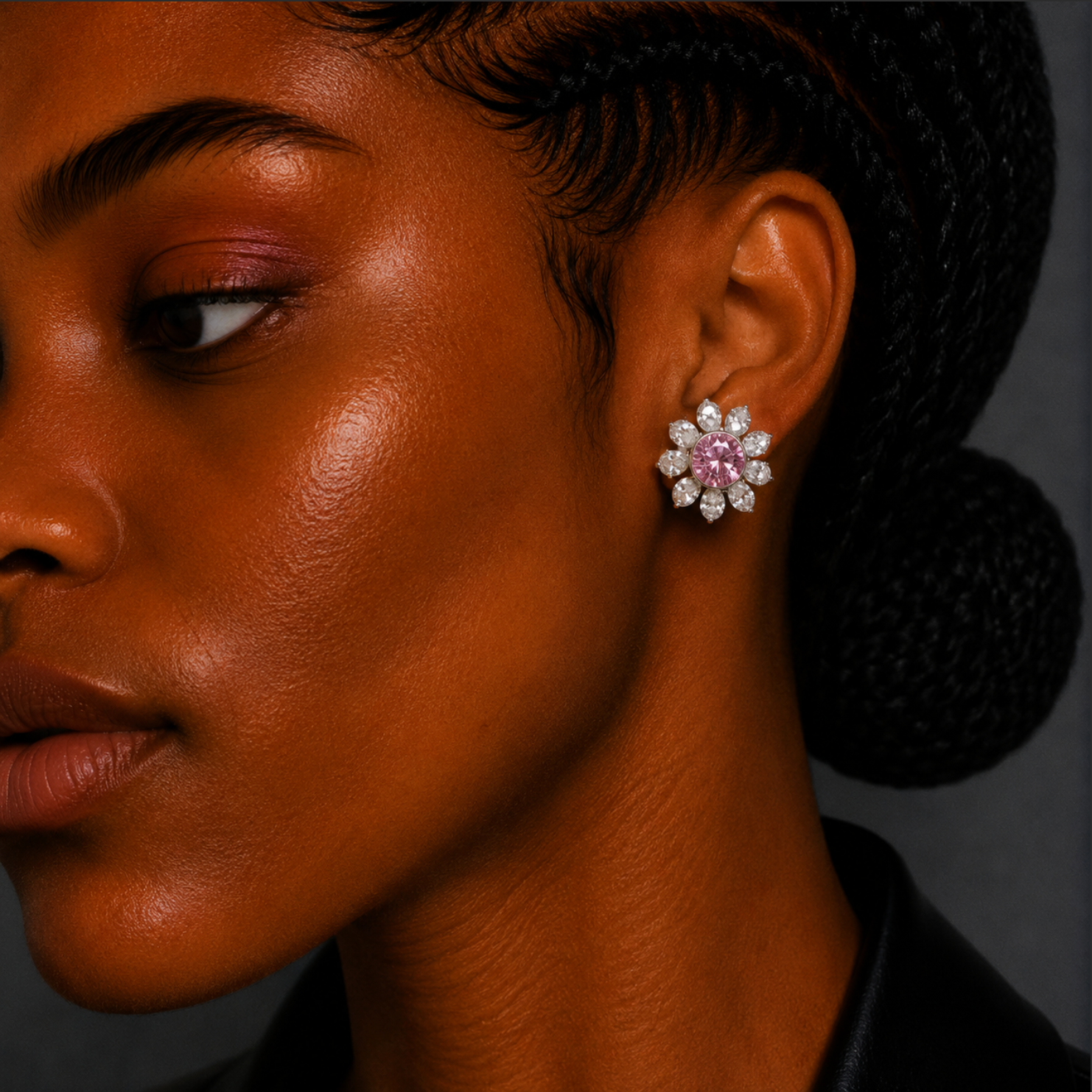 Close-up of a person wearing a sparkling earring with pink gemstones.