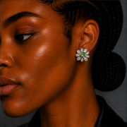 Close-up of a woman wearing a diamond earring with a green gemstone.