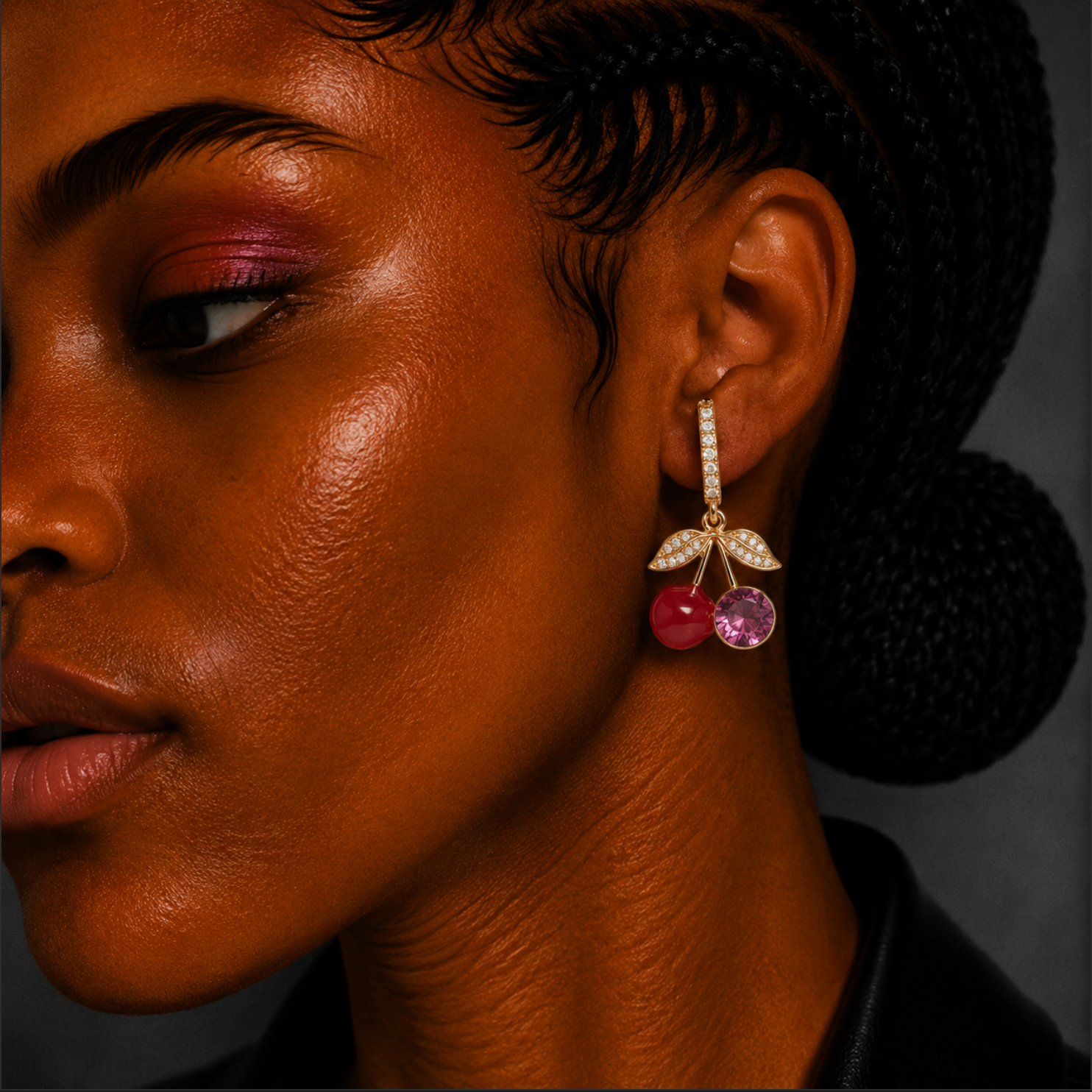 Close-up of a person wearing a cherry-themed earring with a dark background