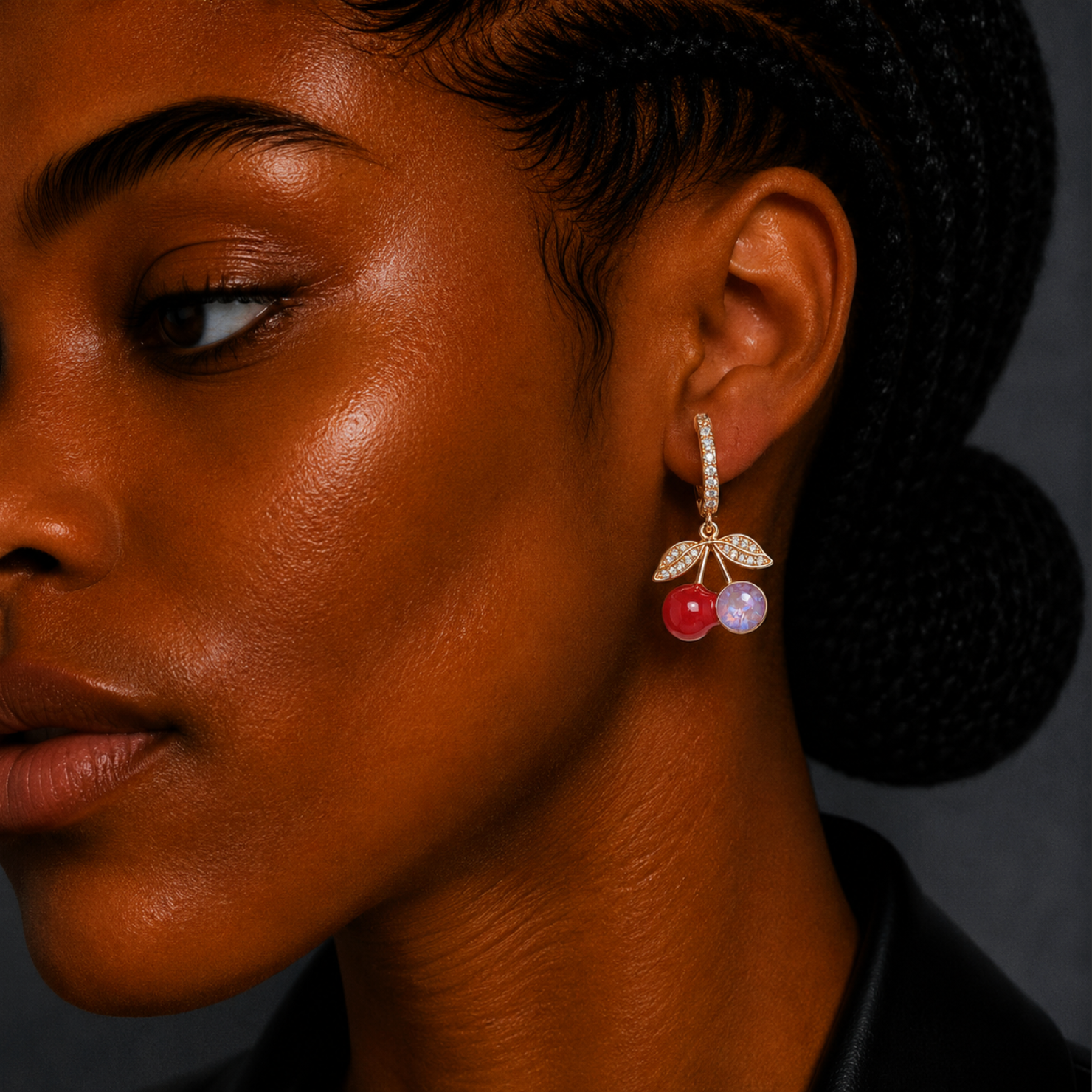 Close-up of a woman wearing a cherry-themed earring with a dark background